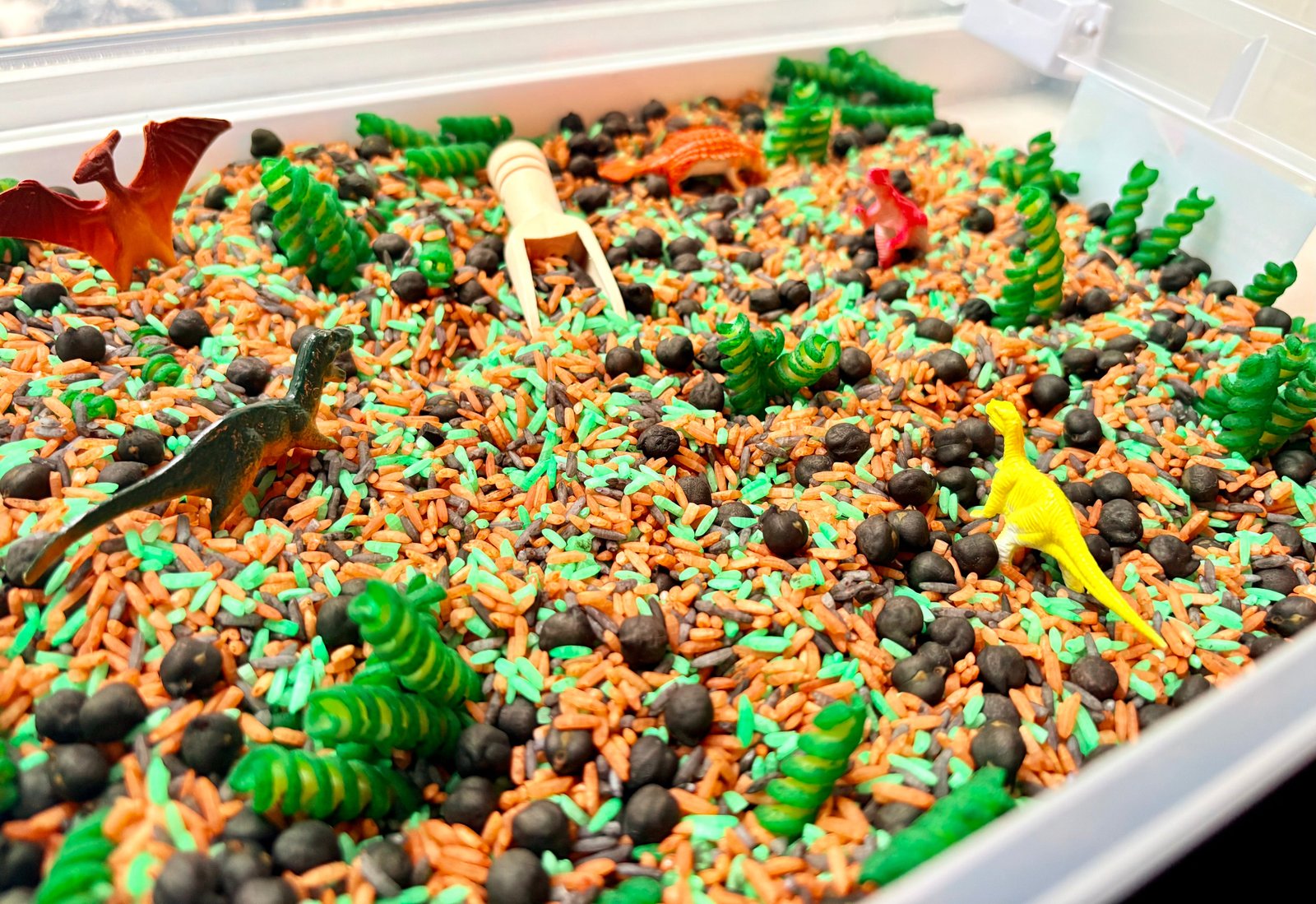 Close-up of colourful dinosaur-themed sensory filler and dinosaur play pieces